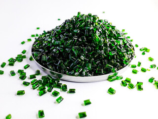 Clear green masterbatch granules in a cup, isolated on white background. Color pigment carrier...