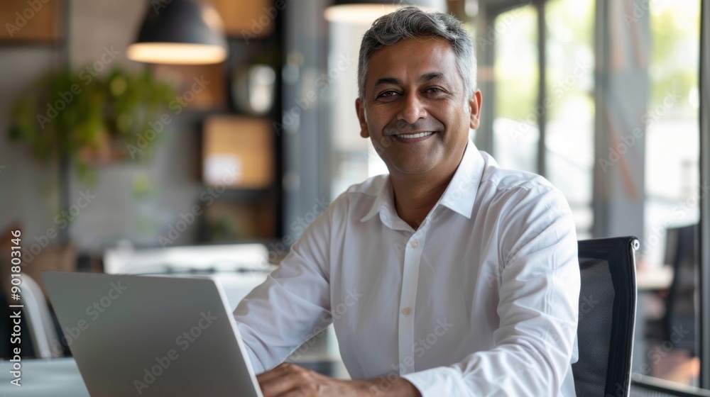 Poster a man is sitting at a desk with a laptop in front of him