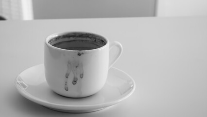 Turkish coffee cup with coffee drops around it on white and black isolated background.