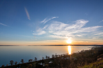 View from a hill over a lake in the evening. Beautiful landscape shot in nature. Romantic sunset in...