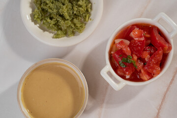 Red, yellow and green sauce in bowls on light background