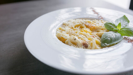 pasta carbonara with yolk, on a white plate with basil, close-up photo