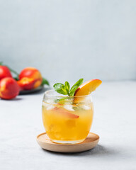 Refreshing peach cocktail, lemonade or iced tea on a light blue background. Concept of a cold non-alcoholic summer drink