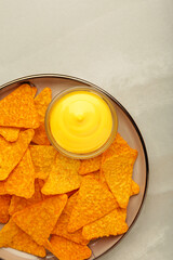 Tasty nachos with cheese sauce on light background. Vertical photo