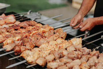 Frying shish kebab on the skewers in brazier. Fresh ruddy meat for barbecue grill on fire outdoor.