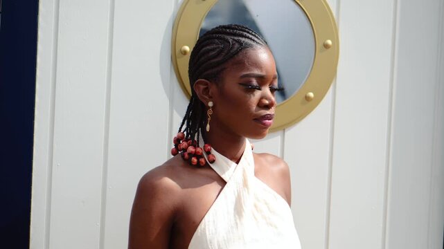 Black woman posing in front of a boat window, in the morning sun