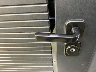 The image shows a detailed closeup view of a door handle that is affixed to a sturdy metal door, highlighting its design and functionality and providing insight into its purpose