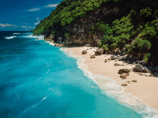 Drone view of scenic coastline with turquoise ocean and tropical sandy beach in Bali island.