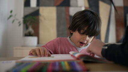 Child yawning while studying with a parent, showing a mix of tiredness and dedication, highlighting the everyday realities of education and parental support at home