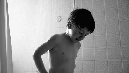 Young boy crying under shower, black and white photo of distressed child during bath time, emotional moment, wet hair and skin, bathroom scene, child hygiene, tears and water droplets