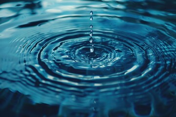 Close-up of a single water droplet creating ripples in tranquil blue water