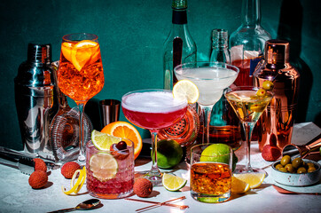 Cocktails. Strong drinks and aperitifs, bar tools, bottles on dark green background, hard light