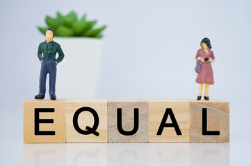 Equal letters on wooden cube blocks with miniatures man and woman including copy space.