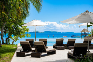 lounge chairs and umbrellas on the beach，Fiji holiday, with the blue skies and seawater of the...
