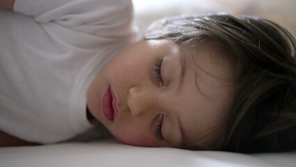 Child sleeping peacefully on a bed, with a serene and relaxed expression, capturing the innocence and tranquility of childhood slumber in a cozy and secure environment
