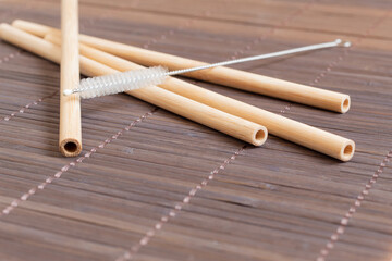Four biodegradable straws and a cleaning brush on a bamboo mat. Environmentally friendly product. Image with copy space.