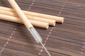 Reusable bamboo straws with cleaning brush on bamboo mat. Recyclable utensil.