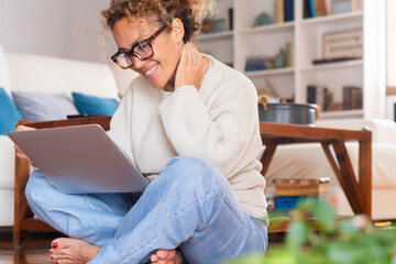 Fototapeta premium Simple living lifestyle. One woman sitting on the floor at home barefoot using laptop to surf the net and watching contents. Modern female managing small business in digital job lifestyle. Video call