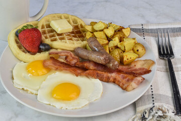 fried eggs with sausage , bacon and waffles