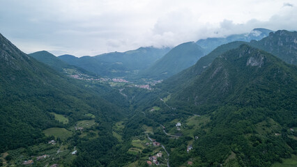 Naklejka premium Breathtaking Aerial View of Lush Green Valley Surrounded by Majestic Mountains in Early Morning Light