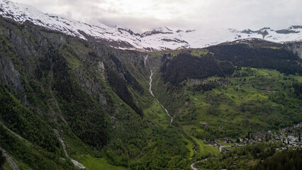 Majestic Snow-Capped Mountains Overlooking Lush Green Valley During Cloudy Day