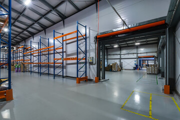 Spacious Industrial Warehouse With Shelving Racks and Open Loading Area.The interior of a large...