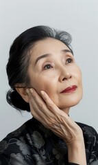 Fototapeta premium An elder Asian woman looks upwards with a contemplative expression