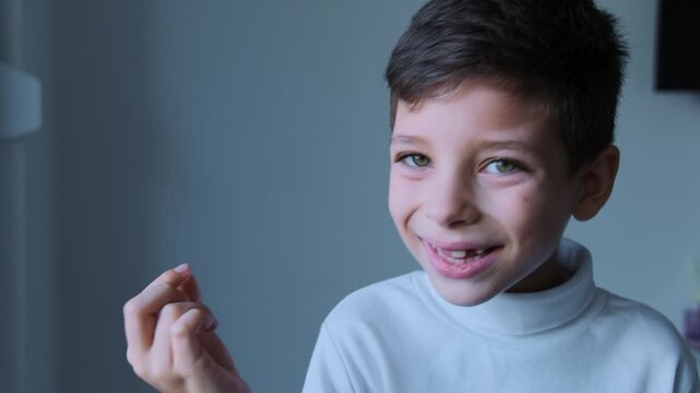 A thrilled boy with a big smile proudly holding up his lost tooth, capturing a joyful and memorable childhood moment