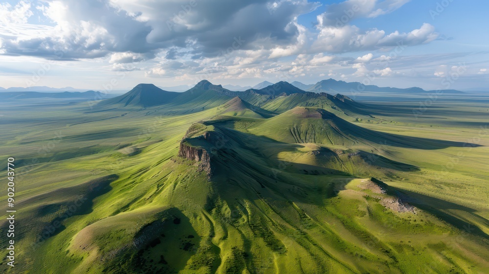 Aufkleber a vast, green field with a mountain range in the background. the mountains are covered in grass, giv