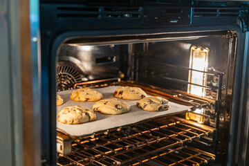 Homemade Chocolate chips cookies baking in the oven, selective focus.