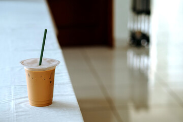palm sugar milk coffee, served with ice cubes in a plastic cup and placed on a white table. selective focus, good for article