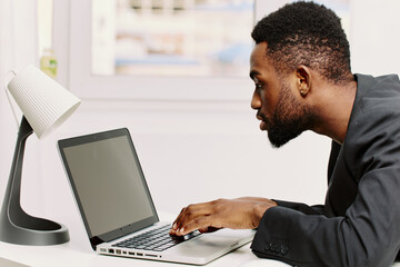 Business professional focused on work, typing on laptop at modern office desk