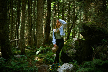 a girl walks through a summer mountain forest