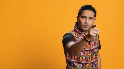 Disappointed indian man admonishing friend over debacle, isolated over studio background. Upset...