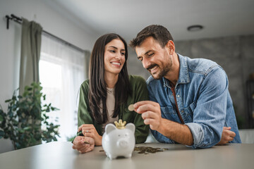 Adult couple save money coins in the piggy bank at home
