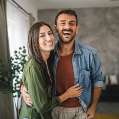 Portrait of beautiful couple stand, smile and hug at home