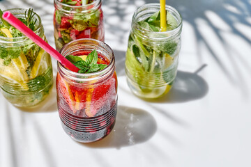 Detox drink. Different varieties of infused water with lemon, berries and herbs. Refreshing summer homemade cocktail. Fresh healthy cold beverage.
