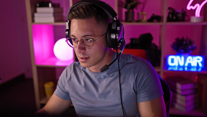 Young hispanic man wearing headset in a colorful gaming room at night, focused and ready to play.