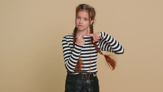 Angry preteen child girl kid showing fig negative gesture, you don't get it anyway. Rapacious, avaricious, acquisitive. Body language. Refusal fig sign. Teenager children isolated on beige background