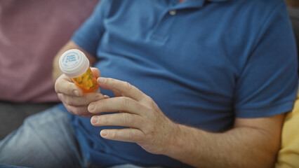 A middle-aged man examines a prescription bottle of pills at home, highlighting healthcare and domestic life.