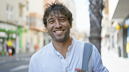 Fototapeta premium Handsome hispanic man with beard and green eyes smiling on a sunny urban street