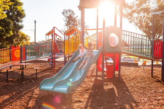 Park playground in afternoon light with children playing on slide - Powered by Adobe