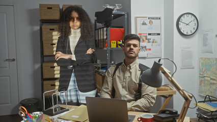 Two investigators, a man and a woman, posed sternly in a cluttered detective office filled with...