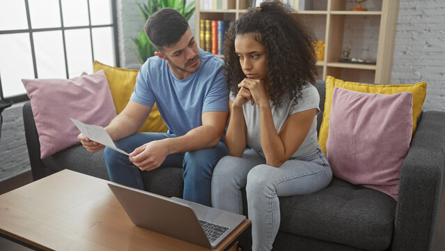 A concerned couple sits together in their living room, with a man and woman examining documents, reflecting relationship and family issues indoors.
