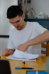 Fototapeta premium A young man repairs shoes at home.