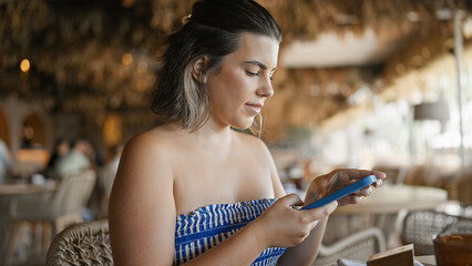 Young hispanic woman taking pictures to the food sitting on the table at the restaurant