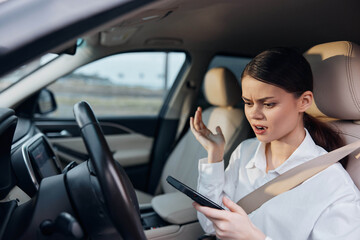 Woman driving car and holding cell phone, looking at screen with hands on steering wheel, emphasizing distracted driving and mobile phone usage while operating vehicle