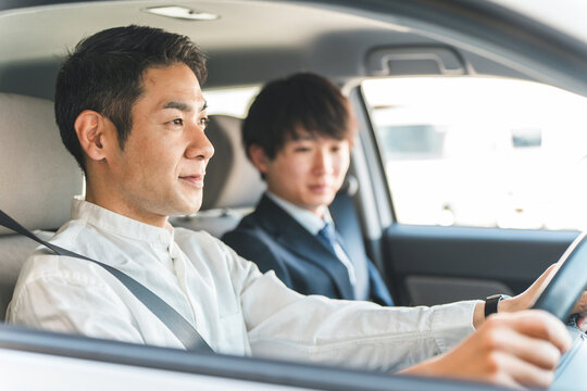 教習所で運転免許を取得するため受講する中年の男性ドライバーと教官の男性
