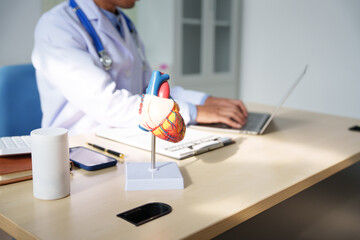 A medical doctor is working at a desk, analyzing patient data related to heart attacks and calculating medical costs to ensure accurate billing and financial management in the healthcare setting.