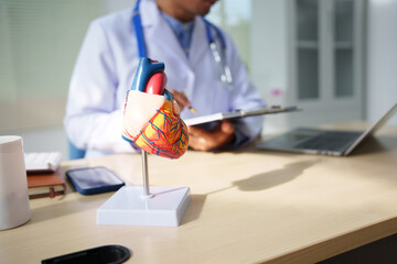 A medical doctor is working at a desk, analyzing patient data related to heart attacks and calculating medical costs to ensure accurate billing and financial management in the healthcare setting.